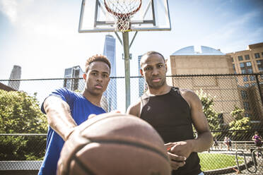 Zwei afroamerikanische Athleten spielen Basketball im Freien - Basketballer trainieren auf einem Platz in New York - DMDF07352