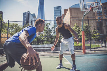 Zwei afroamerikanische Athleten spielen Basketball im Freien - Basketballer trainieren auf einem Platz in New York - DMDF07353