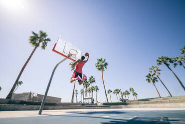 Basketballspieler macht einen Dunk - Sportlicher Mann macht einen spektakulären Dunk im Freien - DMDF07370