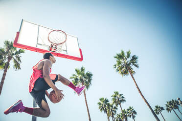 Basketballspieler macht einen Dunk - Sportlicher Mann macht einen spektakulären Dunk im Freien - DMDF07372