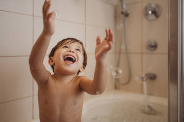 Cheerful boy bathing and enjoying with soap bubbles in bathtub - ANAF02216