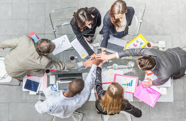 Ein Team von Geschäftsleuten reicht sich während eines erfolgreichen Treffens die Hände - CEO und Manager in einem Firmenbüro, Konzepte über Teamarbeit und Einigkeit, Blick von oben - DMDF07379
