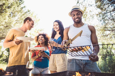 Happy multiracial friends having fun at picnic barbecue garden party - DMDF07392