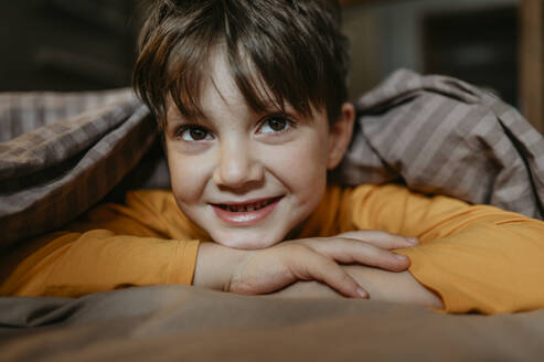 Cute boy resting head on arms at home - ANAF02230