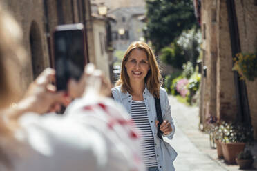 Tourist fotografiert lächelnden Freund in Gasse an sonnigem Tag - JSRF02651