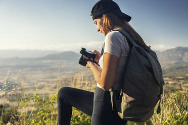 Junger Tourist mit Rucksack und Kamera beim Wandern an einem sonnigen Tag - JSRF02655