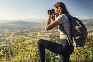 Junger Tourist mit Rucksack beim Fotografieren an einem sonnigen Tag - JSRF02656