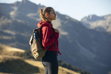 Junge Frau mit Rucksack beim Wandern an einem sonnigen Tag - JSRF02664