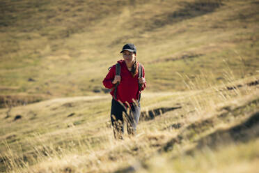 Frau beim Wandern auf einem Berg an einem sonnigen Tag - JSRF02671