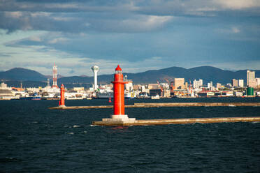 Der ikonische rote Leuchtturm erhebt sich vor der malerischen Kulisse des Hafens von Hakodate in Hokkaido, Japan - RHPLF28214