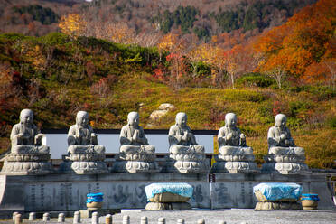 Reihe von sechs Shizo-Statuen mit einer schönen Herbstlandschaft im Hintergrund, Osorezan Bodaiji-Tempel, Mutsu, Präfektur Aomori, Honshu, Japan, Asien - RHPLF28227
