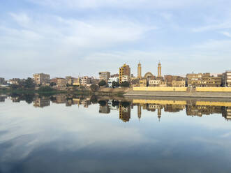 Blick auf Gebäude, die sich im Wasser des Nils spiegeln, Dendera, Ägypten, Nordafrika, Afrika - RHPLF28239