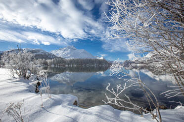 Clouds over snowy woods on shores of frozen Lake Sils in winter, Engadine, Canton of Graubunden, Switzerland, Europe - RHPLF28495