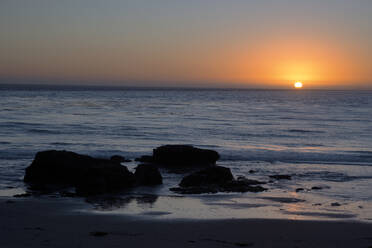 Sunset over the ocean, with rocks in the foreground, San Simeon, California, United States of America, North America - RHPLF28580