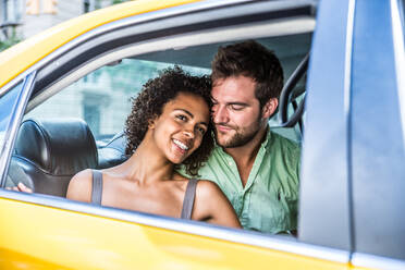 Interracial couple driving on a taxi in Manhattan - Tourists sightseeing New York on a yellow cab - DMDF07440