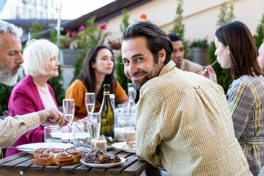 Storytelling footage of a multiethnic group of people dining on a rooftop. Family and friends make a reunion at home - DMDF07467