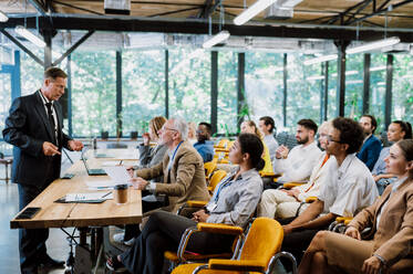 Cinematic image of a conference meeting. Business people sitting in a room listening to the motivator coach. Representation of a Self growth and improvement special event - DMDF07485