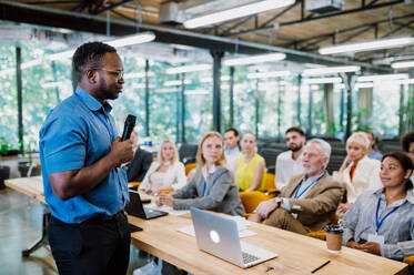 Cinematic image of a conference meeting. Business people sitting in a room listening to the motivator coach. Representation of a Self growth and improvement special event - DMDF07498