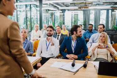 Cinematic image of a conference meeting. Business people sitting in a room listening to the motivator coach. Representation of a Self growth and improvement special event - DMDF07504