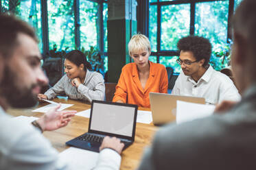 Cinematic image of people working in a start up business. Multiethnic team of experts working together to develop the new projects - DMDF07523