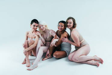 Beauty image of a group of women with different age, skin and body posing  in studio for a body positive photoshooting. Mixed female models in lingerie  on colored backgrounds stock photo