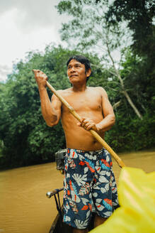 Von unten reifen shirtless lokalen Mann hält Ruder beim Rudern auf authentischen Boot in schmutzigen Fluss des Amazonas-Regenwaldes - ADSF48026