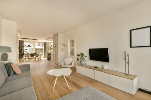 Interior of modern living room with sofa and television against open dining room and window in contemporary apartment - ADSF48072