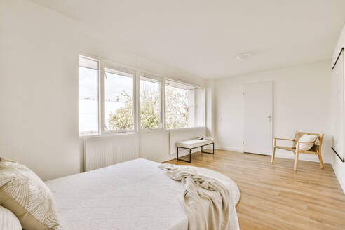 Interior of spacious bedroom with comfortable bed and large bright windows in contemporary house with white walls - ADSF48083