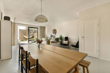 Interior of open plan modern apartment with dining room and stylish living room with large window surrounded with white light walls - ADSF48091