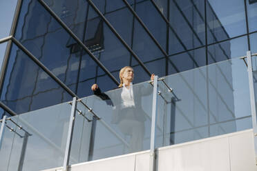 Businesswoman leaning on glass railing at terrace - OSF02228