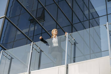 Geschäftsfrau lehnt an Glasgeländer auf Terrasse - OSF02228