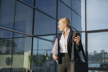 Geschäftsfrau mit Umhängetasche vor einem Bürogebäude stehend - OSF02232