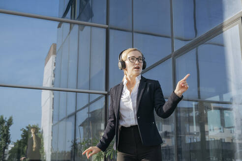 Geschäftsfrau beim Musikhören vor einem Bürogebäude - OSF02238