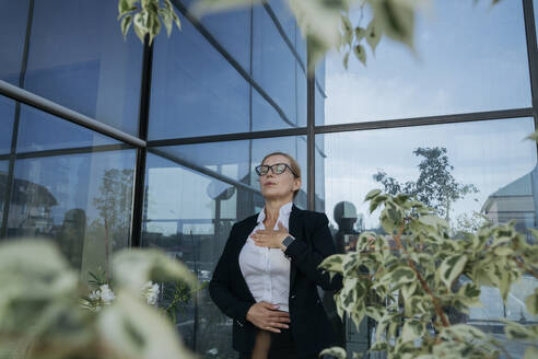Businesswoman practicing breathing exercise on terrace - OSF02246