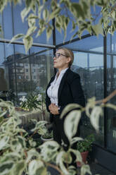 Businesswoman practicing breathing exercise on terrace of business center - OSF02247