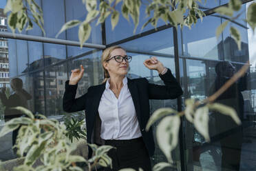 Contemplative businesswoman standing in front of glass building - OSF02248