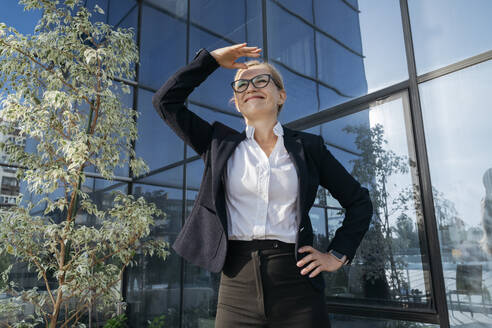 Smiling businesswoman shielding eyes on sunny day - OSF02249