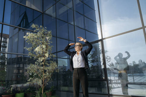 Geschäftsfrau schützt ihre Augen auf der Terrasse eines Geschäftszentrums - OSF02250