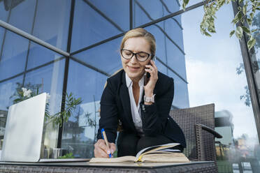 Lächelnde Geschäftsfrau, die im Business Center mit ihrem Handy telefoniert - OSF02252