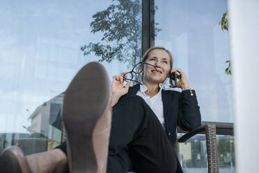 Businesswoman talking over mobile phone sitting at business center - OSF02257