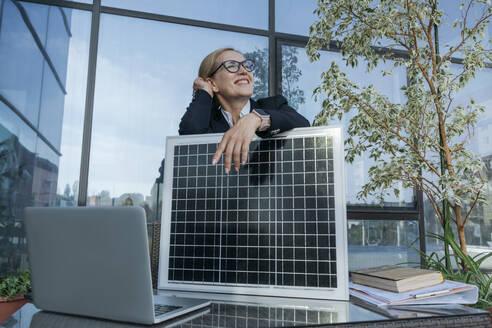 Nachdenkliche Geschäftsfrau mit Sonnenkollektor auf der Terrasse des Geschäftszentrums - OSF02263