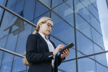 Businesswoman using smart phone by office building - OSF02266