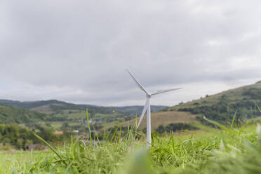 Wind turbine model on grass under cloudy sky in meadow - OSF02281