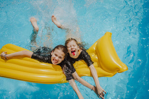 Glückliche Freunde, die Spaß haben und sich an einem sonnigen Tag auf ein Floß im Pool lehnen - MDOF01583