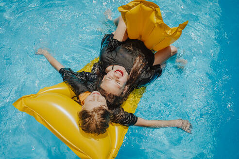 Freunde liegen auf einem Floß und schwimmen über Wasser an einem sonnigen Tag - MDOF01586