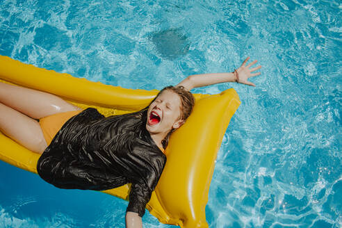 Happy girl screaming and lying on airbed in swimming pool - MDOF01588