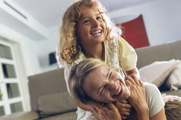 Happy girl embracing mother in living room - JSRF02694