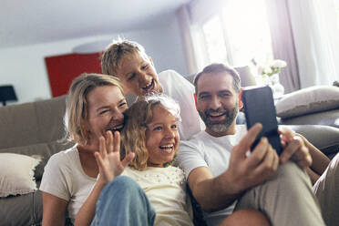 Cheerful family taking selfie on mobile phone at home - JSRF02708