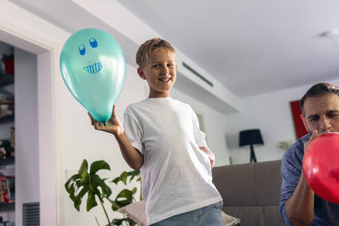 Lächelnder Junge mit Luftballon bei seinem Vater zu Hause - JSRF02719