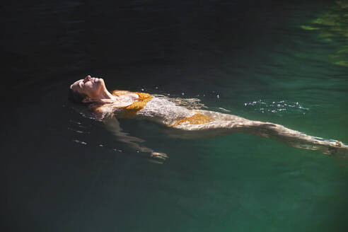 Woman floating on water in river - PCLF00765